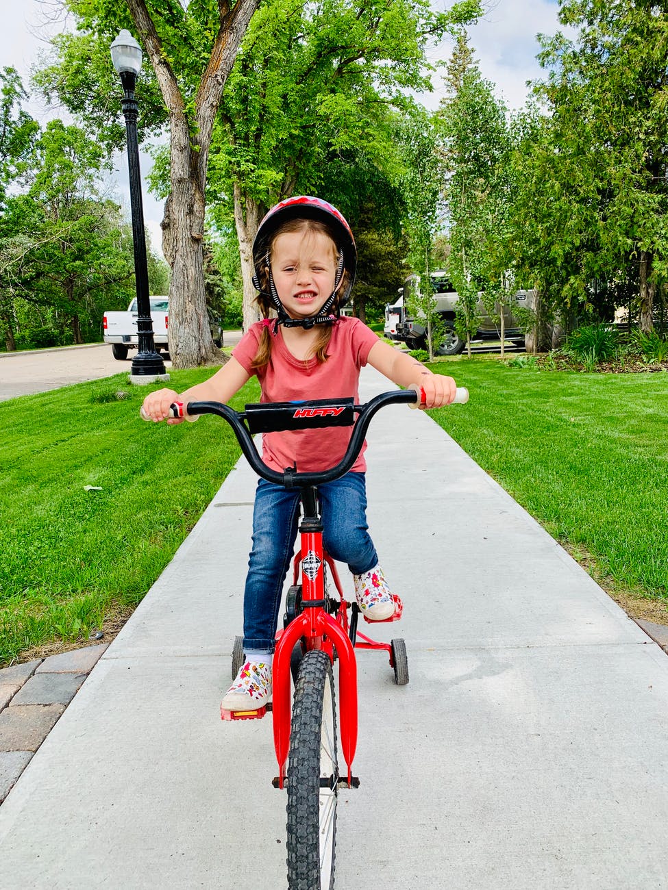photo of young girl riding bike by sidewalk
